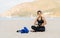 A beautiful young girl of Asian appearance in sportswear is sitting on the sand beach and getting ready