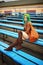 Beautiful young girl with bag posing on bench on football stadium