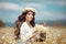 Beautiful young girl with basket of flowers over chamomile field. Carefree happy brunette woman with healthy wavy hair having fun