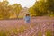 The beautiful young girl in a blue dress and cap walks across the field of a lavender, long curly hair, smile, pleasure