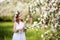 Beautiful young girl in blue dress in the garden with blosoming  apple trees. Cute girl  holding apple-tree branch