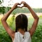 beautiful and young girl depicts a heart with her hands above her head.