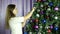 Beautiful young girl dresses up the Christmas tree close up cute