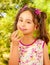 Beautiful young girl, eating a healthy apple and colorful dragees in her lips, in a blurred garden background