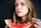 A beautiful and young girl eats a juicy watermelon. The juice drips down her chin.