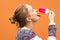 Beautiful and young girl eats a pink hue ice cream and enjoys. She catches a drop of melted ice cream with her tongue and smiles.