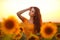 Beautiful young girl enjoying nature on the field of sunflowers at sunset. Summertime. Attractive brunette woman with long healthy