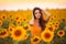 Beautiful young girl enjoying nature on the field of sunflowers at sunset. Summertime. Attractive brunette woman with long healthy