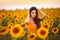 Beautiful young girl enjoying nature on the field of sunflowers at sunset. Summertime. Attractive brunette woman with long healthy