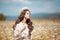 Beautiful young girl with flower enjoying in chamomile field. Carefree happy brunette woman with chaplet on healthy wavy hair