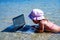 Beautiful young girl freelancer escapes from the heat at sea and working remotely with netbook in water