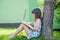 Beautiful young girl freelancer relaxing under a tree and working with laptop, freelancer workplace, dream job. Office concept