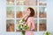 Beautiful young girl in a gently pink dress, holding a bouquet of roses in one hand. Happy woman holding a straw hat on the backgr