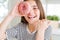 Beautiful young girl kid eating sweet pink donut pointing and showing with thumb up to the side with happy face smiling