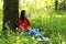 Beautiful young girl Listen to music on a mobile phone while sitting under giant oak