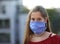 Beautiful young girl with long brown hair and surgeon mask durin