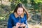 Beautiful young girl with long dark blond hair in a denim jacket and with a phone in her hands is resting in a green park