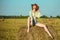 Beautiful young girl with long thin legs and naked belly in a cowboy hat and denim shorts on the yellow field poses