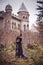 Beautiful young girl in a long vintage dress standing against the background of an old manor.