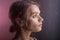 Beautiful young girl looks away on purple background. blurry drops of water run down the glass in front of her face