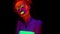 A beautiful young girl painted with glowing paint posing in black light talking. Pretty woman with glowing bodyart