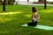 Beautiful young girl in park practices yoga and relaxes. Calm and tranquility