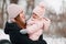 Beautiful young girl in a pink jumpsuit playing with her mother in a snowy winter park