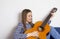 A beautiful young girl plays on an acoustic guitar.