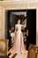 A beautiful young girl in a powdery wedding dress on the background of the interiors of a luxurious historical apartment.