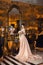 A beautiful young girl in a powdery wedding dress on the background of the interiors of a luxurious historical apartment.