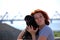 The beautiful young girl with red hair embraces on the street of the pet a black dog of breed a pug.