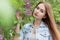 Beautiful young girl with red hair in the garden with lilac