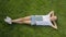 Beautiful young girl relaxing on green grass at park with book