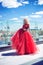 Beautiful young girl on the roof of a building in a red lush dress