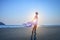 Beautiful young girl with short hair in a long white dress on sandy beach by the sea during sunset. Counter light