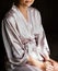 Beautiful young girl in silk robe sitting on chair and crosses.