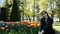 A beautiful young girl sits on a lawn in a summer park next to a club of colorful tulips