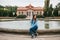 Beautiful young girl sits next to a fountain in the park and has a rest