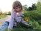 Beautiful young girl sitting next to a coniferous plant. Undersized thuja in the park. The mysterious look of a child. Sun and sun