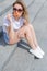 Beautiful young girl sitting on the stairs in shorts and sunglasses and eating a delicious ice cream bright