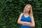 Beautiful young girl smiles in a blue dress, against a background of hedges of wild grapes. Copy space