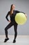 Beautiful young girl in sportswear is engaged in training with a big gymnastic ball.