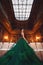 Ð beautiful young girl standing in a haute couture green dress in a luxurious interior.