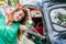 Beautiful young girl straightens her hair in the mirror of an old vintage car