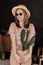 Beautiful young girl in a straw hat holds a cactus in her hands