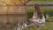 Beautiful young girl in summer dress with long hair feeds birds near a city pond in a park. Recreation. Summer.