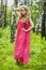 Beautiful young girl in a summer dress at sunset. Fashion photo in the forest. Model in a pink long dress, with flowing curly hair