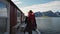 Beautiful young girl traveler go to the wooden pier on the background of traditional red rorbu traveling to Lofoten