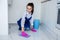 Beautiful young girl washes the floor with her hands. Bucket of water for cleaning