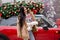 Beautiful young girl is wearing winter clothes holding sparklers near red car with decorated xmas tree on the roof